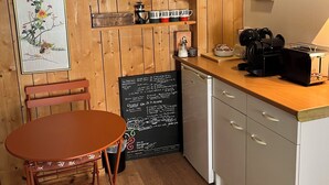 A cozy kitchen with wooden walls, a dining table, chairs, a coffee machine, and a chalkboard menu. - B&B Les Truffières in the heart of nature (Trémolat)