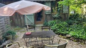 A patio with a table and chairs, a wooden fence, and a garden area. - B&B Les Truffières in the heart of nature (Trémolat)