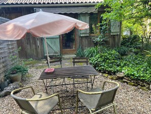 Une terrasse avec une table et des chaises, une clôture en bois et un espace jardin.