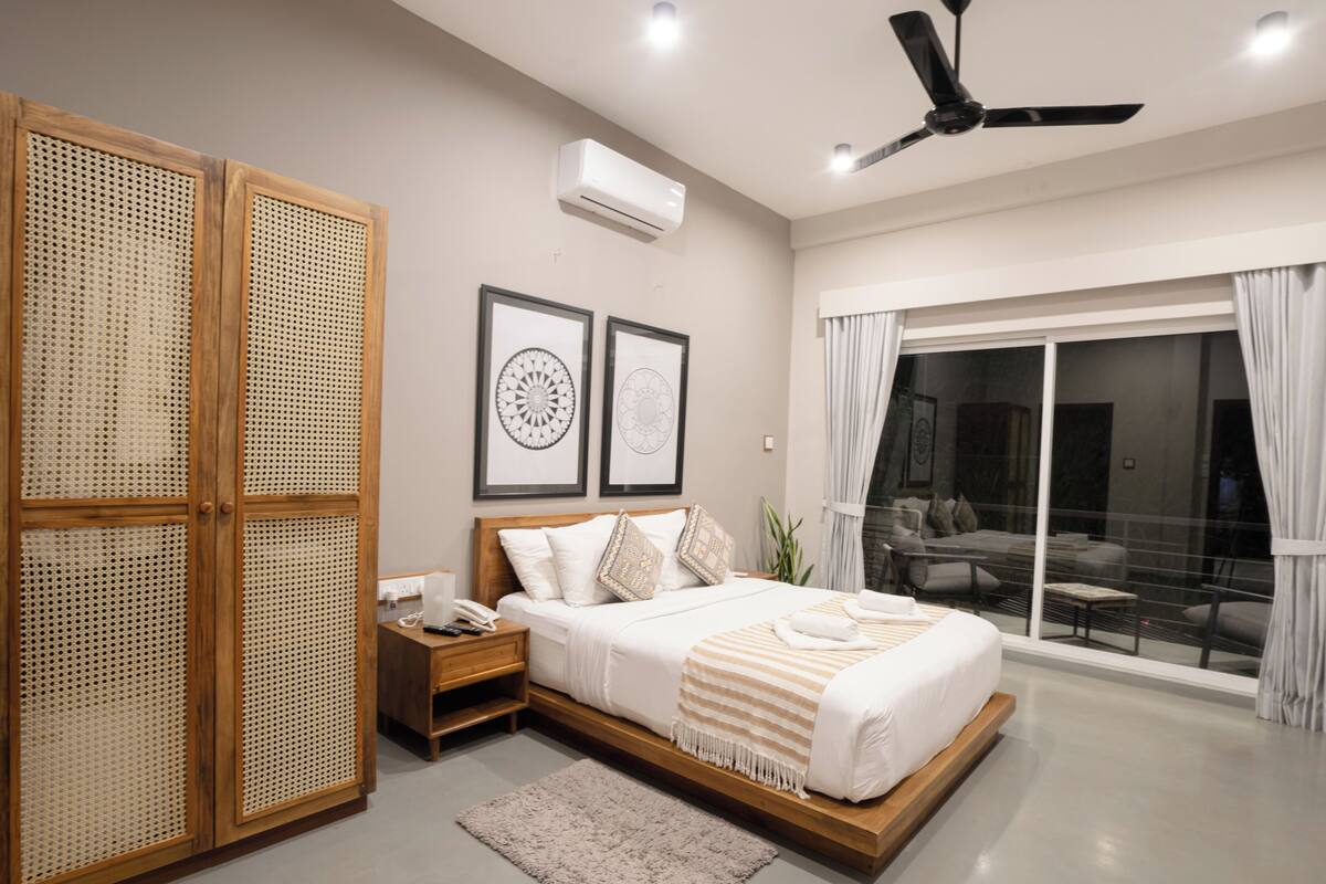 A modern bedroom with a bed, nightstand, and a large window with a view.