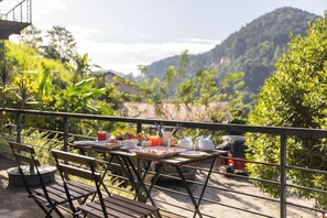 A dining table set outdoors with a view of a mountainous landscape. - The Cubes Ella  (Ella)