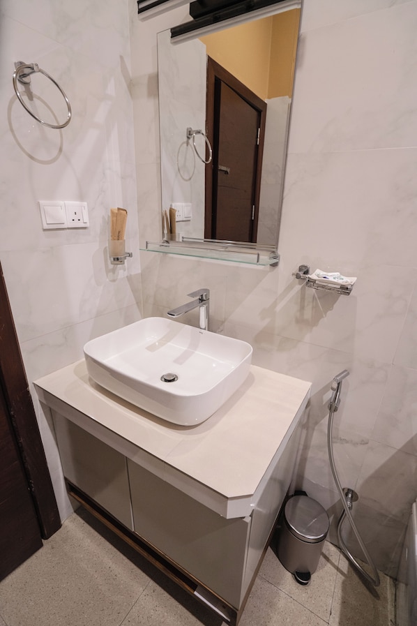 A modern bathroom with a white sink, a mirror, a towel ring, and a glass shower enclosure. - The Cubes Ella (Ella)