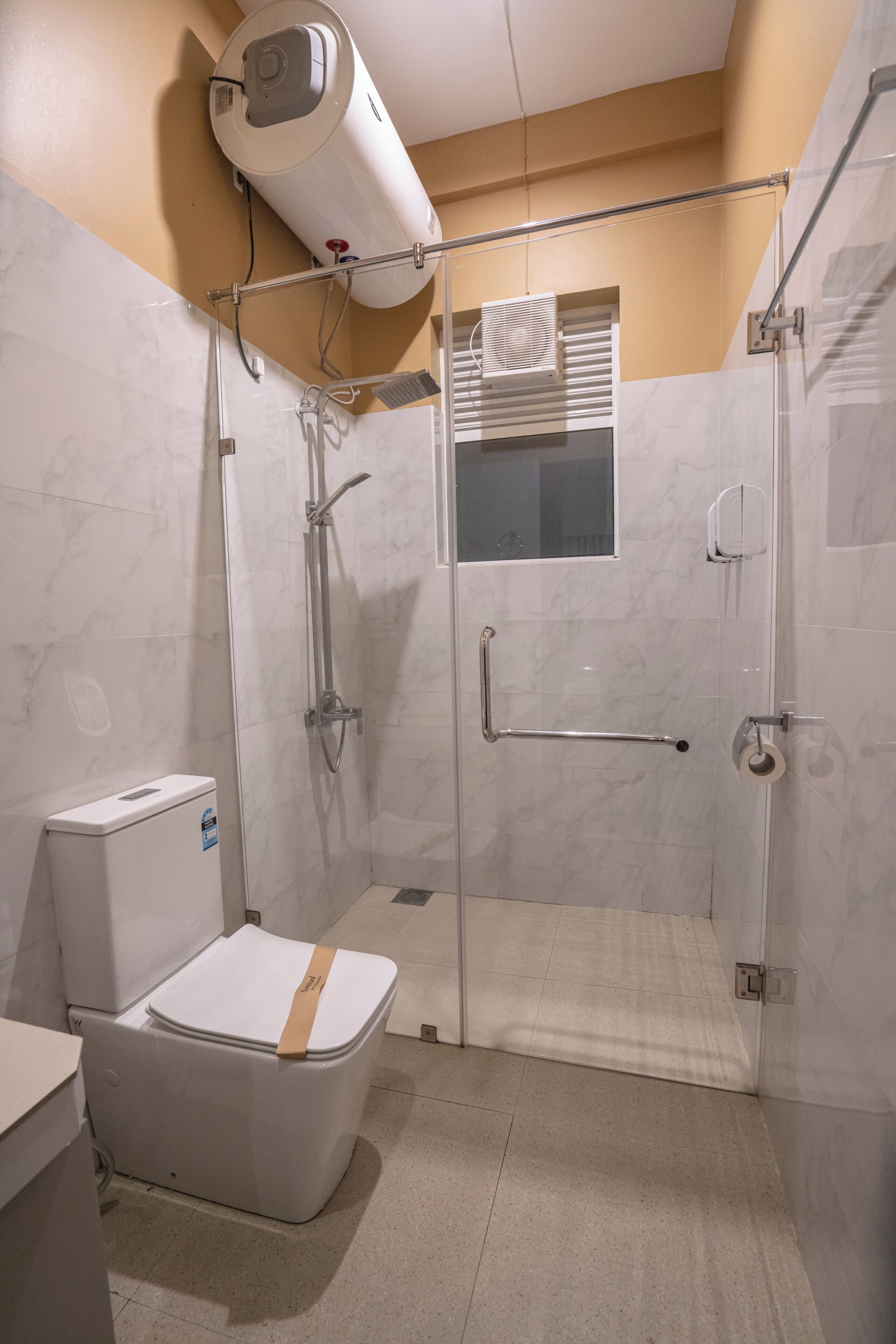 A bathroom with a shower, toilet, and a towel rack.