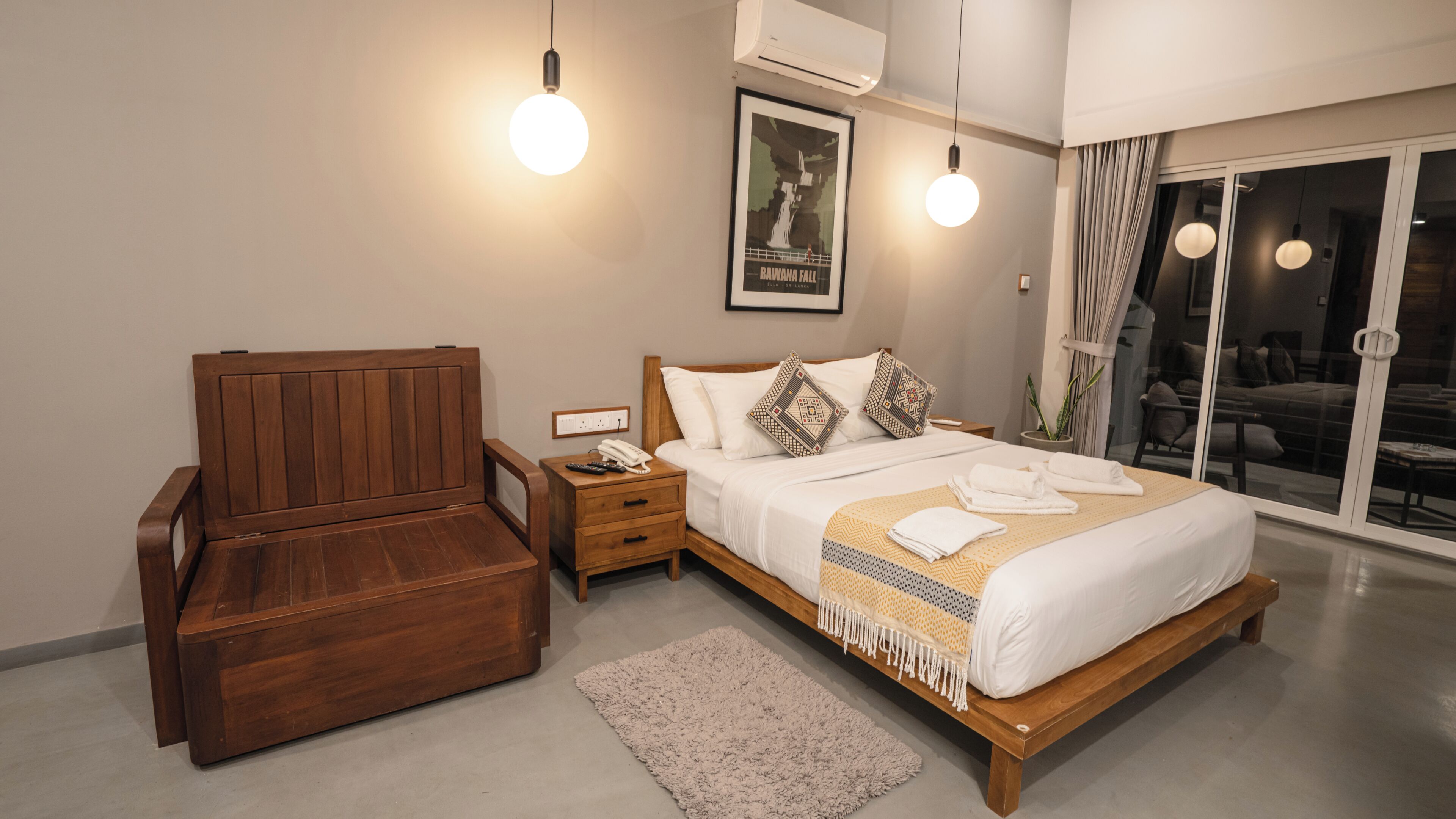 Un dormitorio moderno con cama de madera, mesitas de noche, un sofá, un ventanal grande y un equipo de aire acondicionado.