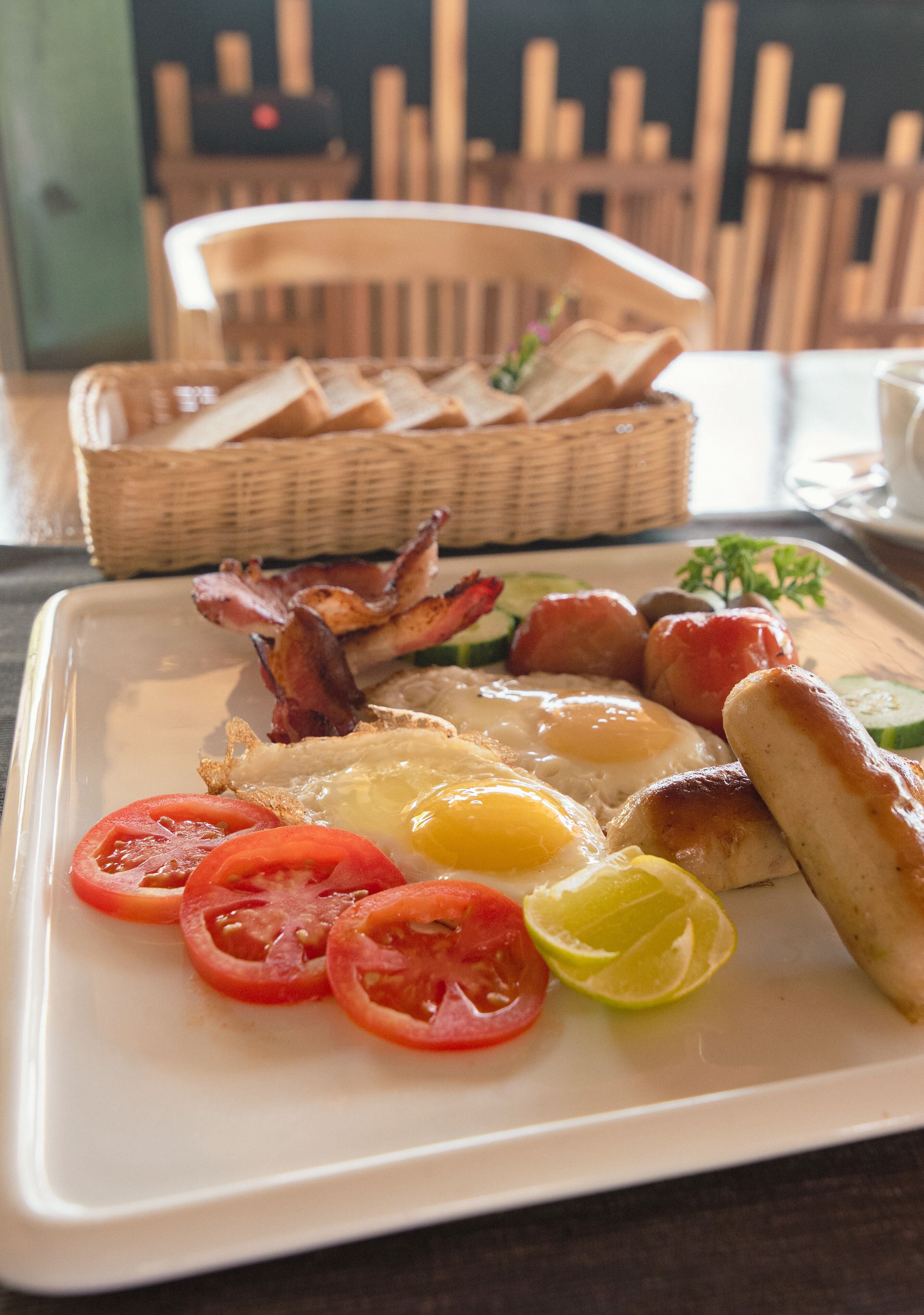 A breakfast plate with eggs, bacon, sausages, tomatoes, and toast.