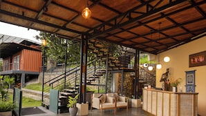 A modern lobby with a staircase, a reception desk, and a seating area. - The Cubes Ella  (Ella)