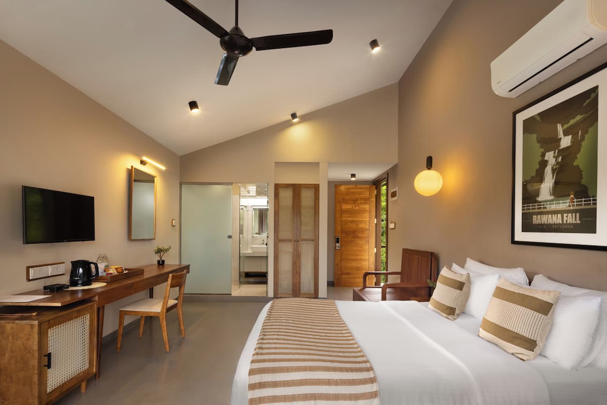 A modern hotel room with a bed, desk, chair, and a television.