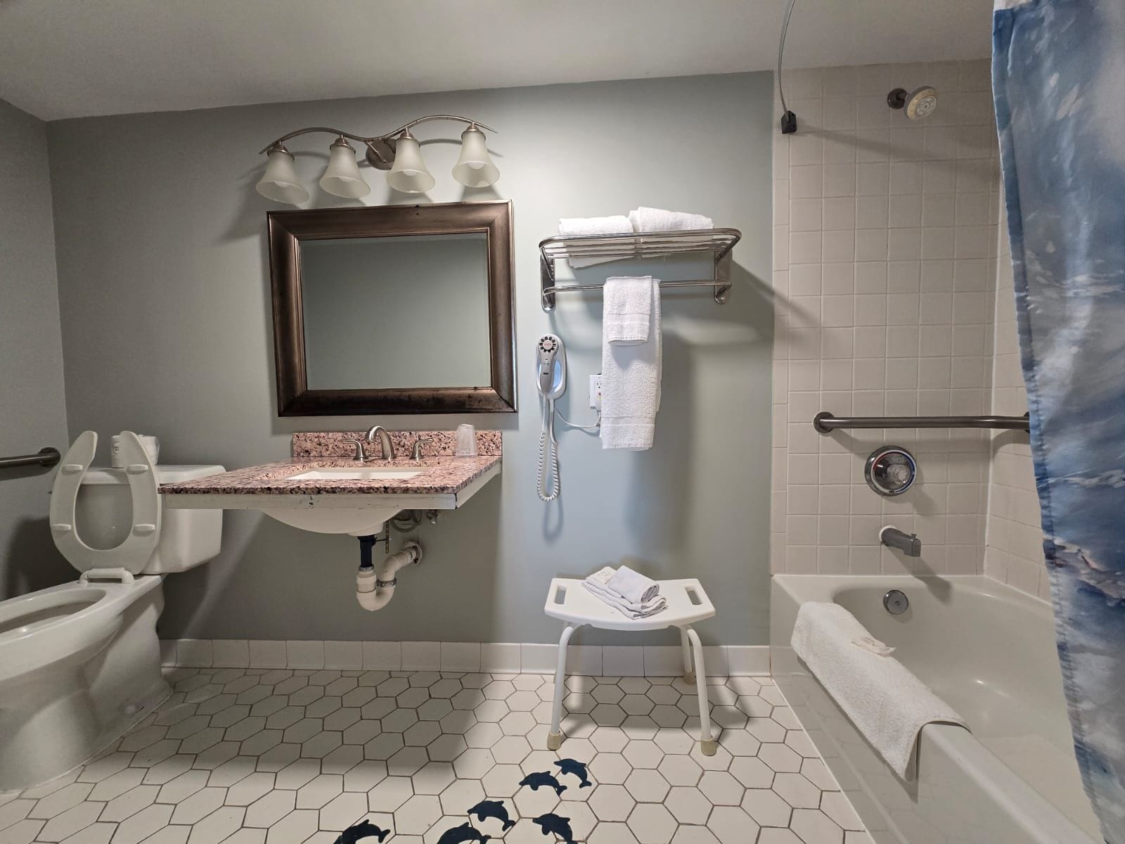 A bathroom with a sink, mirror, towel rack, toilet, and shower area.