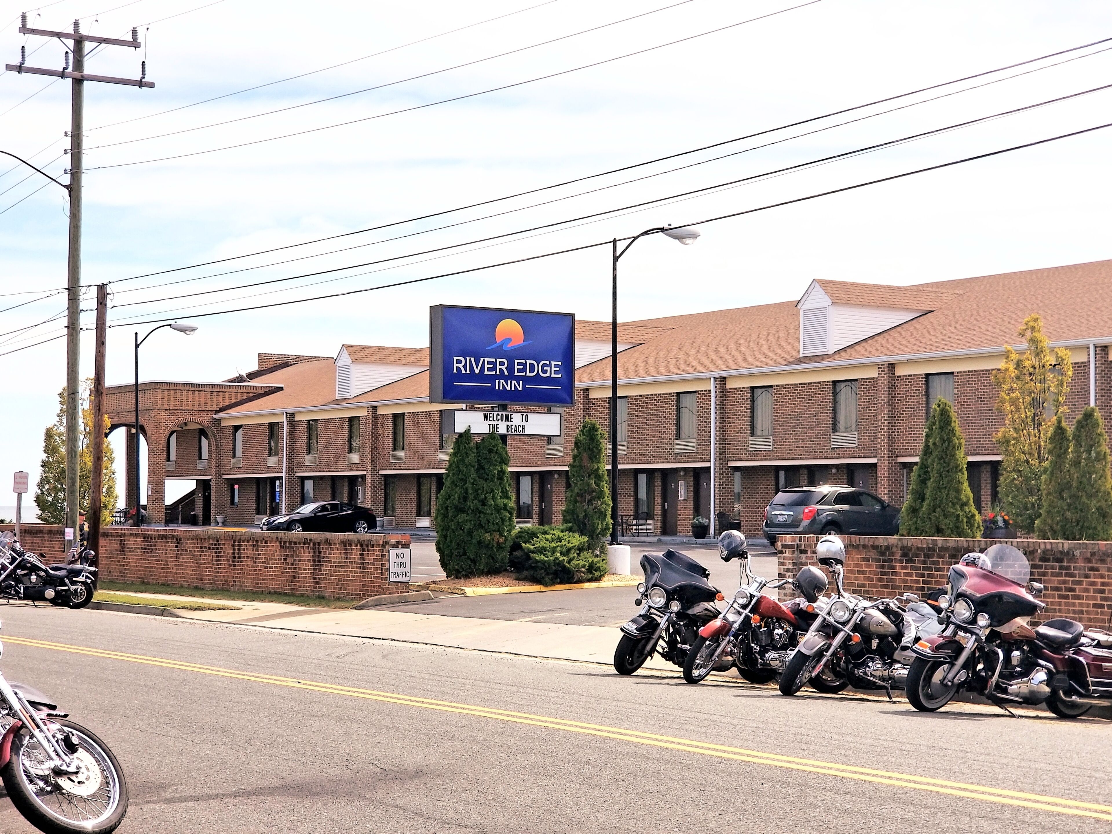 A motel with a sign reading "River Edge Inn" and a welcome sign for the beach.