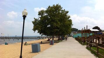 A beach with a wooden fence, a lamppost, and a clear sky.