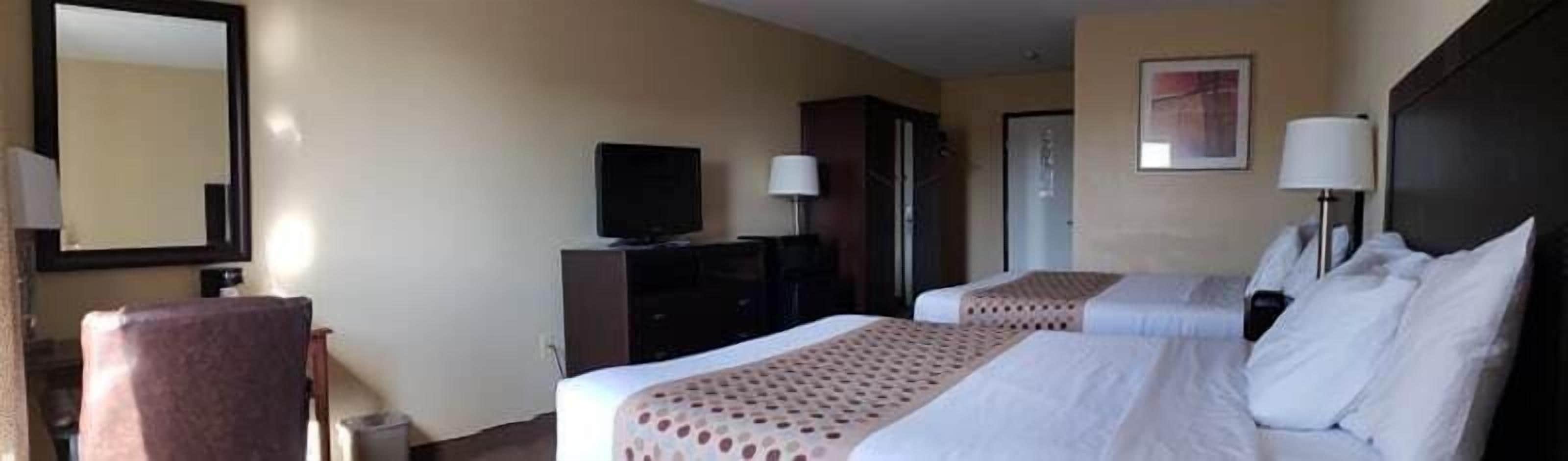 Habitación de hotel con dos camas, un escritorio, una silla, un televisor y un armario.