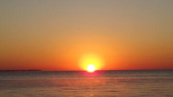 Un atardecer sobre un mar tranquilo con un horizonte despejado.