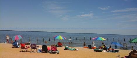 A beach with colorful umbrellas, chairs, and people enjoying the water.