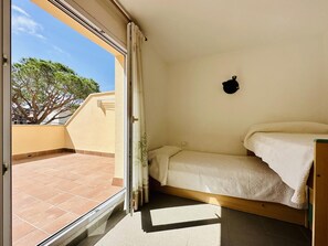 A small room with a bed, a window, and a view of a tree and building outside. - Brisa CostaBravaSi - Beach, A/C, Parking (Platja d'Aro)