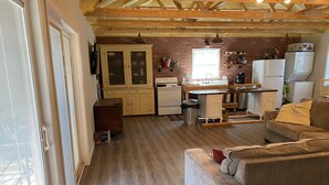 A spacious kitchen with wooden beams, a dining area with a sofa, and a large window providing natural light. - Edina Missouri New Cabin in Rural Area (Edina)