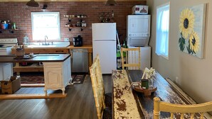A rustic kitchen with exposed wooden beams, a brick wall, and a large window. - Edina Missouri New Cabin in Rural Area (Edina)
