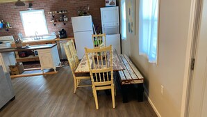 A kitchen with wooden flooring, a dining table with chairs, a refrigerator, and a window with a view. - Edina Missouri New Cabin in Rural Area (Edina)