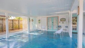 A covered swimming pool with clear blue water, surrounded by white walls and a wooden fence. - ArtSea 1 · 2BR at LECOM, Beaches, Ample Parking -Downtown (Bradenton)