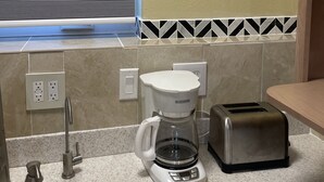 Eine Küche mit Kaffeemaschine, Toaster und einem Fenster mit Jalousien.