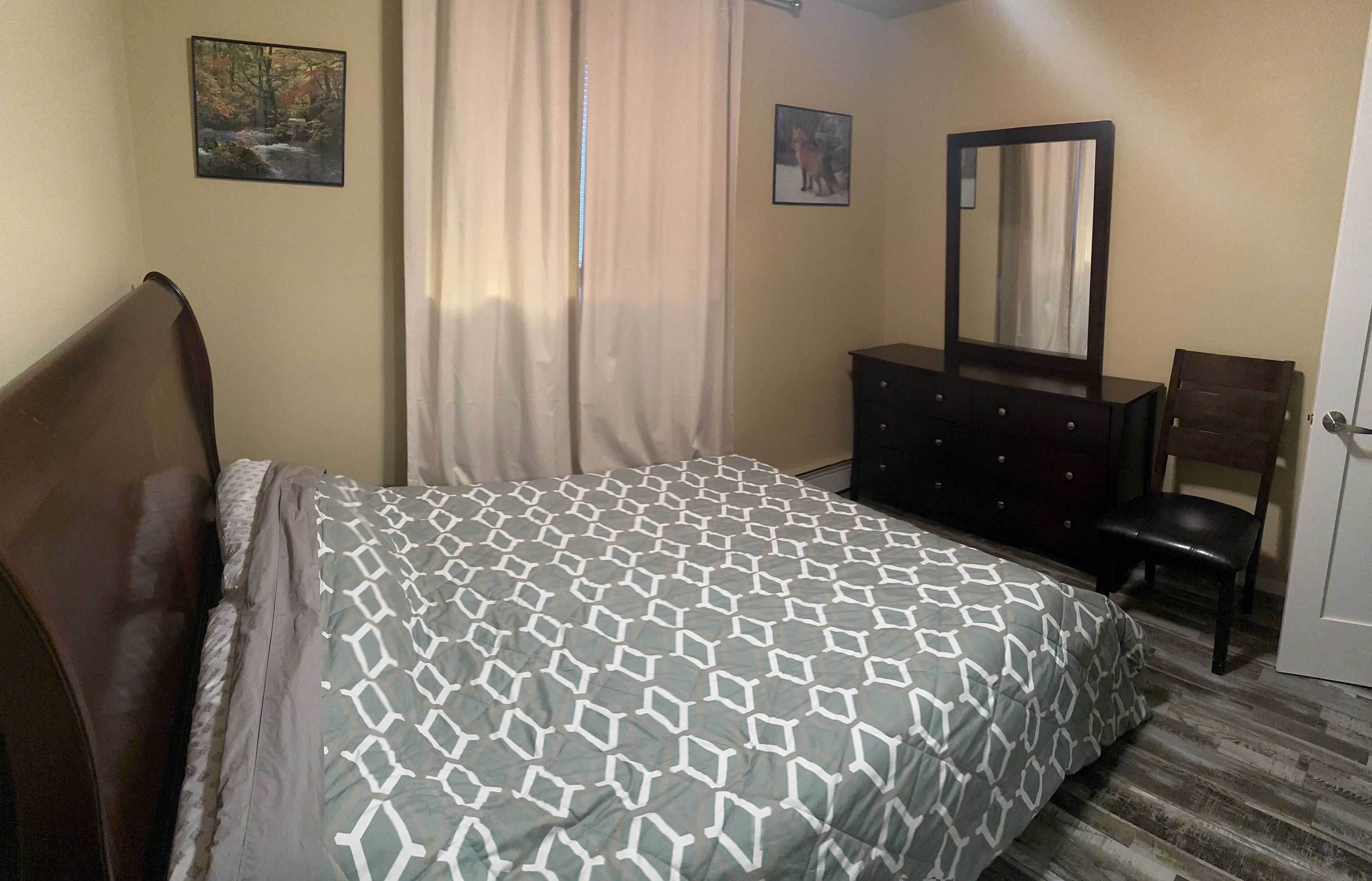 Un dormitorio con cama, cómoda, silla y puerta.