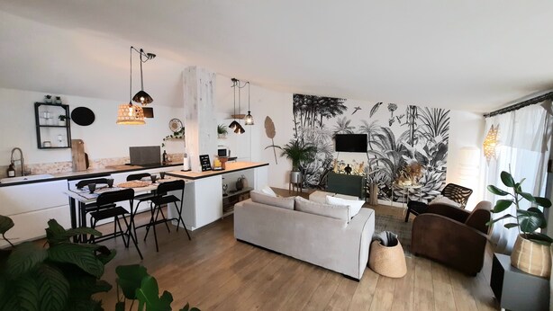 Una cocina moderna con comedor, un sofá y un televisor en la pared.