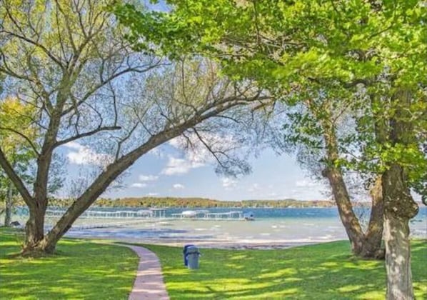 A pathway leading to a waterfront area with trees and a clear view of the water. - Spacious Treetop Cabin Perfect for Large Families! (Bellaire)