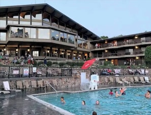 A hotel with a pool area, outdoor seating, and a multi-level building with balconies. - Spacious Treetop Cabin Perfect for Large Families! (Bellaire)