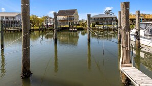 Ein Haus am Wasser mit angestoßenen Booten, Holzpfählen und einem Balkon.
