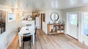 Un comedor con mesa y sillas, una cocina equipada, una estantería y un espejo.