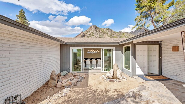 A modern house with a patio, a dining area with chairs, and a garage. - The Desert Trailhead Retreat Phoenix with Pool (Phoenix)