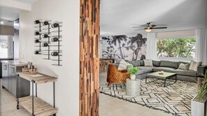 A modern living room with a sectional sofa, a coffee table, and a wall-mounted wine rack. - The Desert Trailhead Retreat Phoenix with Pool (Phoenix)