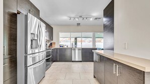 Una cucina moderna con elettrodomestici in acciaio inossidabile, mobili in legno scuro e un'ampia finestra che offre vista sul paesaggio.