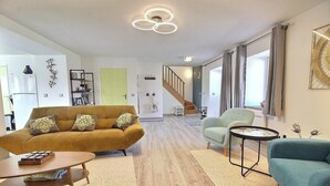 Una sala de estar moderna con un sofá, sillones, una mesa de centro y una escalera que conduce a otro nivel.