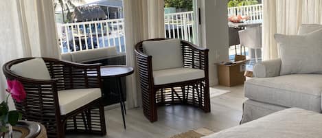 A cozy living area with wicker furniture, a view of the outdoors, and a balcony with a railing.