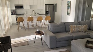 Een moderne woonkamer met een grijze bank, een salontafel en een eethoek met gele stoelen.