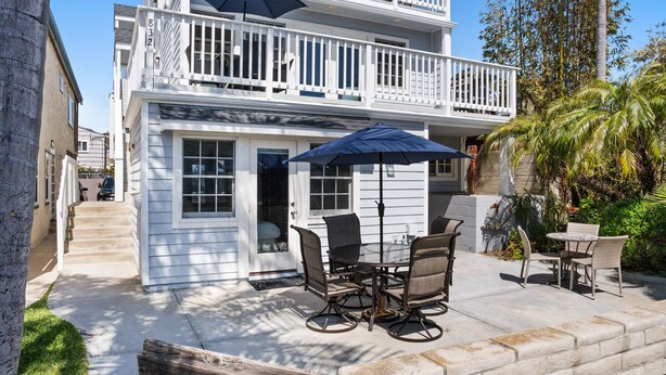A two-story building with a balcony, outdoor seating area with tables and chairs, and a wooden bench. - Spacious Family Beach Getaway | Scenic Bay Views, AC and Parking! (San Diego)