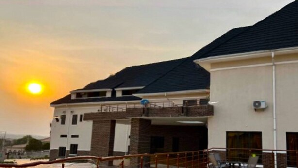 A modern building with a swimming pool, a covered area, and a view of the sunset. - Ibom Waterfall Resorts and Suites (Arochukwu)
