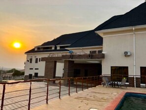 A modern building with a swimming pool, a covered area, and a view of the sunset. - Ibom Waterfall Resorts and Suites (Arochukwu)