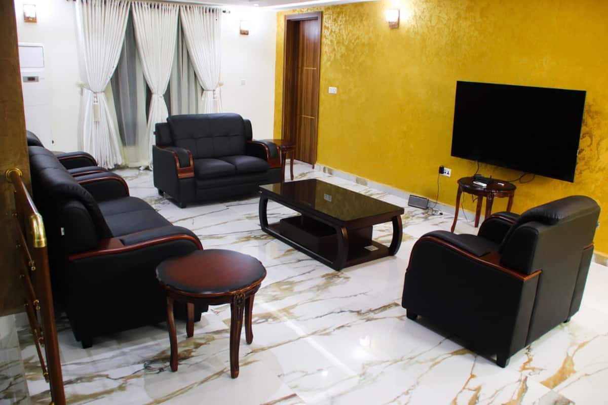Uma sala de estar com sofá, mesa de centro e televisão de tela plana na parede.