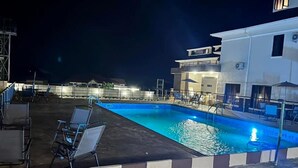 A swimming pool with lounge chairs and a building with balconies in the background. - Ibom Waterfall Resorts and Suites (Arochukwu)