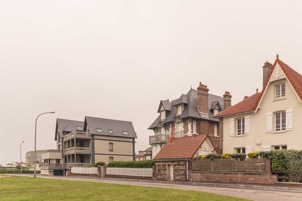 Una hilera de casas residenciales con diversos estilos arquitectónicos, incluyendo una casa moderna de dos pisos y una casa tradicional con techo de tejas rojas.