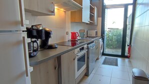 Una cocina compacta con horno integrado, cafetera y microondas.