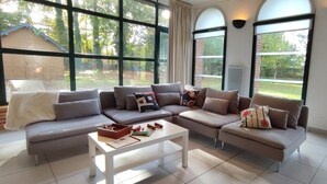 Una sala moderna con un sofá seccional, una mesa de centro y grandes ventanales con vistas al exterior.