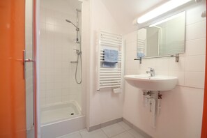 Un bagno con doccia, lavandino e specchio.