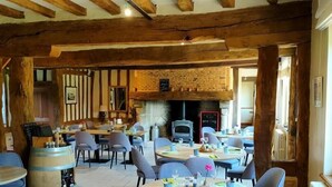 A restaurant with wooden beams, tiled floors, and round tables with chairs.