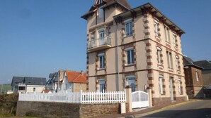 Ein mehrstöckiges Gebäude im klassischen Stil, mit einem markanten Turm und einem Balkon im oberen Geschoss.