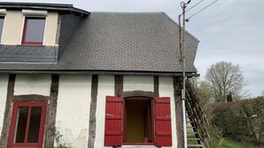 Una casa tradicional con entramado de madera, techo empinado, puerta roja y ventana pequeña.