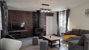Un salon avec un mur en briques, un téléviseur, une cheminée, un canapé et une table basse.