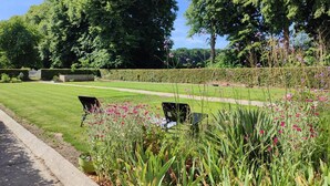Un jardin bien entretenu, avec une pelouse, des parterres de fleurs et un chemin.