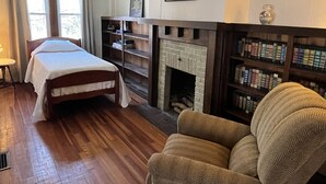 A room with a bed, a fireplace, and bookshelves.